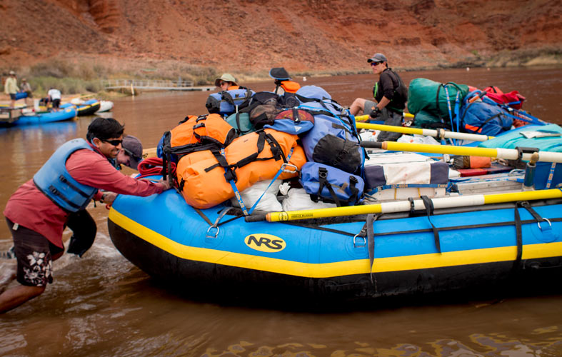 A group of team members launches a gear-filled raft onto the Colorado River