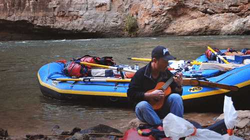 A man plays a ukelele on the shores of the Colorado River